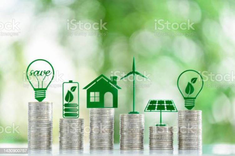 Renewable or clean energy generation prices and costs, financial concept : Green eco-friendly symbols atop coin stacks e.g. energy efficient light bulb, a battery, a solar cell panel, a wind turbine.